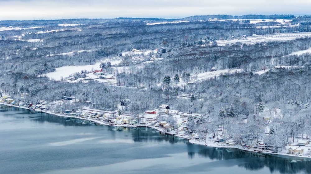 Aerial view of snow-covered hills and homes along the shore of Keuka Lake.
