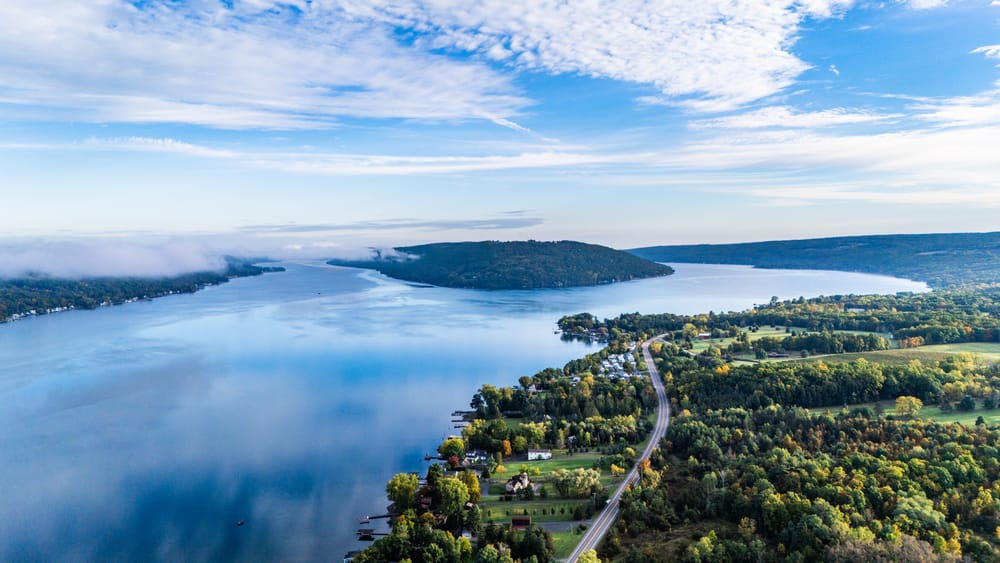 High aerial view of Keuka Lake's Y-shaped branches, blue water, green shoreline, and low morning fog.